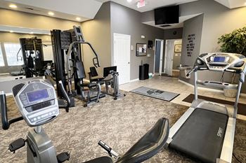 A gym with exercise equipment and a tv on the wall